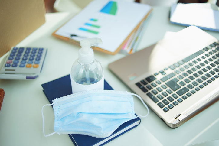 medical mask and hand sanitiser on a desk